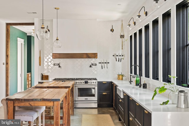 kitchen with tasteful backsplash, high end range, kitchen peninsula, sink, and hanging light fixtures