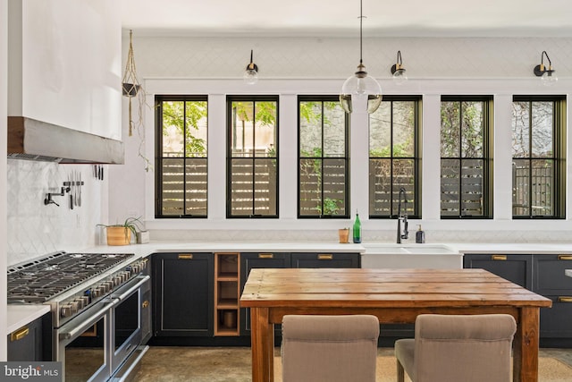 kitchen with a wealth of natural light, high end range, sink, and hanging light fixtures