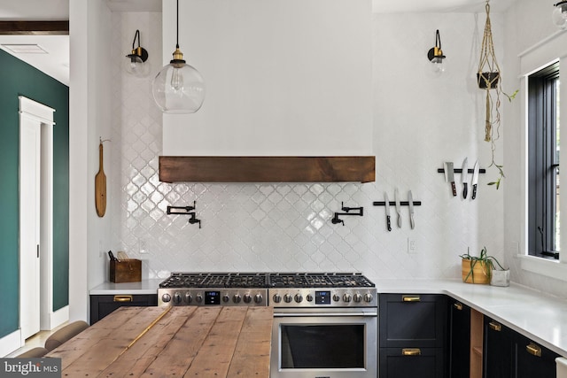 kitchen with hanging light fixtures, custom range hood, high end range, and backsplash