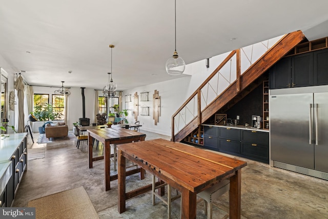 dining space featuring a wood stove, an inviting chandelier, and concrete floors