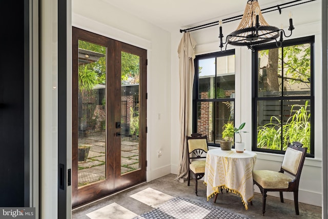 interior space with french doors, an inviting chandelier, and concrete flooring