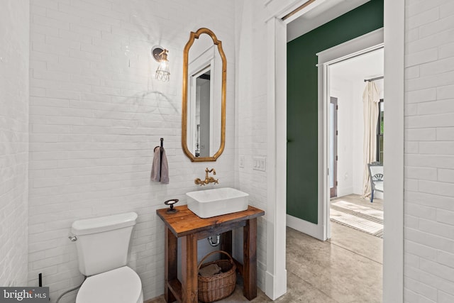 bathroom featuring toilet, sink, and concrete flooring