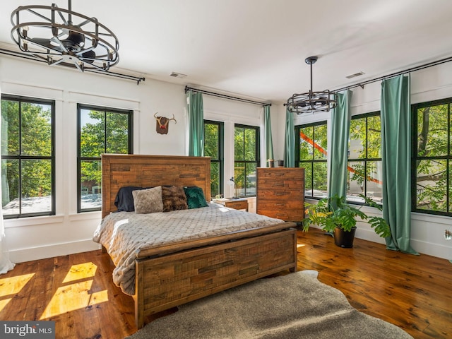 bedroom with dark hardwood / wood-style flooring, a chandelier, and multiple windows