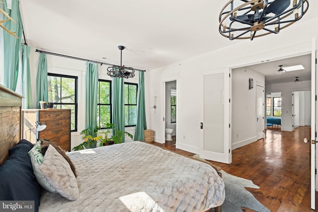 bedroom with dark wood-type flooring, connected bathroom, and a notable chandelier