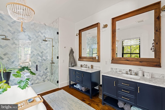 bathroom with wood-type flooring, a shower with door, a chandelier, and vanity