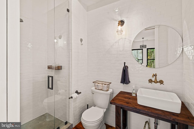 bathroom with tile walls, toilet, sink, and an enclosed shower