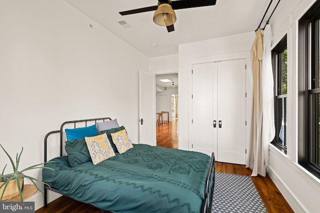 bedroom featuring dark wood-type flooring, ceiling fan, and a closet