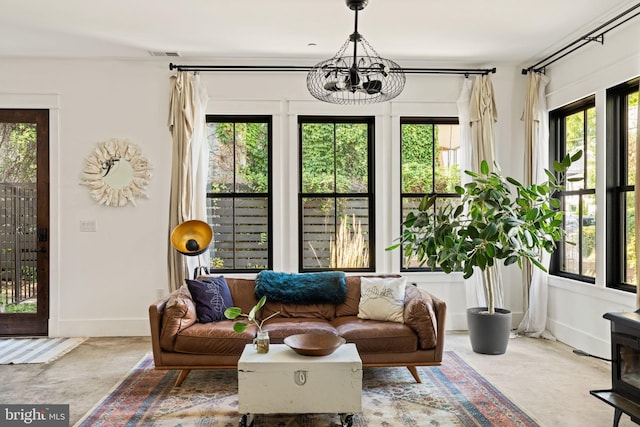 living room featuring a chandelier and concrete flooring