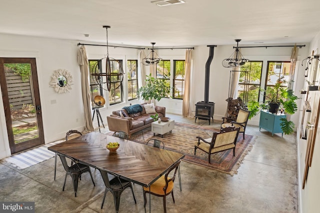 dining space with a wood stove, concrete flooring, and a chandelier