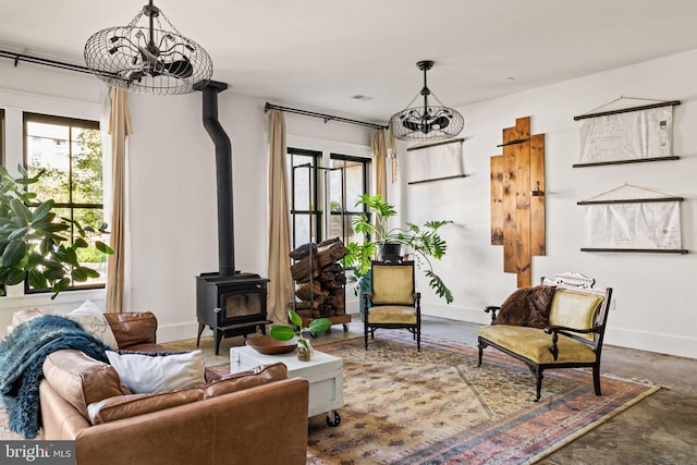 interior space featuring a wood stove, an inviting chandelier, and concrete flooring