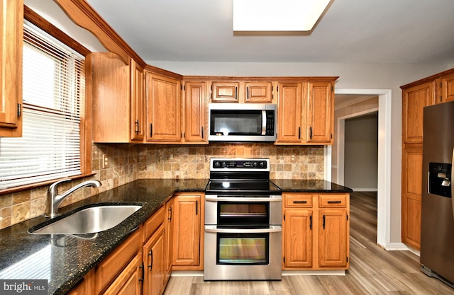 kitchen with stainless steel appliances, plenty of natural light, sink, and light hardwood / wood-style flooring