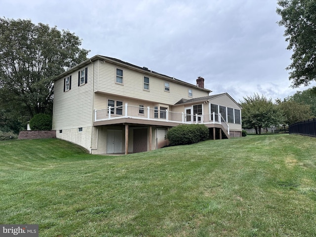 rear view of house with a wooden deck and a lawn