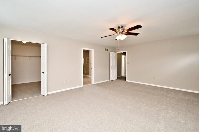 unfurnished bedroom with a spacious closet, a closet, and ceiling fan