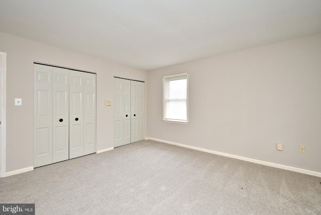 unfurnished bedroom featuring multiple closets and carpet flooring