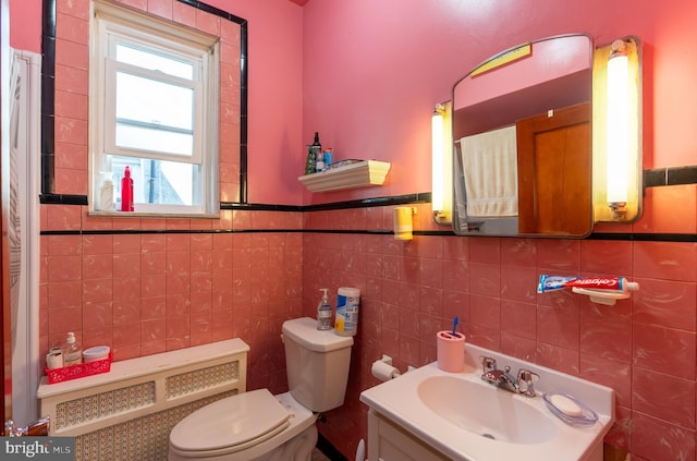 bathroom with radiator, vanity, tile walls, and toilet