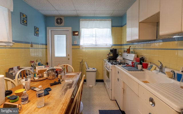 kitchen with sink, wood counters, a paneled ceiling, white range with gas cooktop, and white cabinets