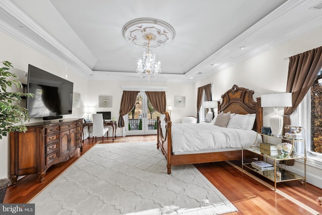 bedroom featuring access to outside, a notable chandelier, hardwood / wood-style flooring, and a tray ceiling