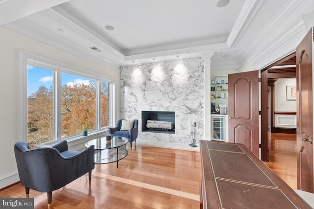 living room featuring ornamental molding, wood-type flooring, a healthy amount of sunlight, and a fireplace