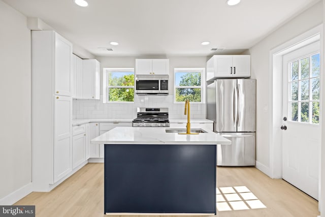 kitchen with a center island, appliances with stainless steel finishes, white cabinetry, and sink