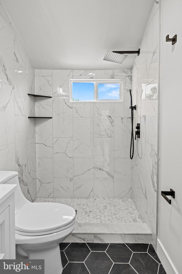 bathroom with vanity, tile patterned flooring, toilet, and tiled shower