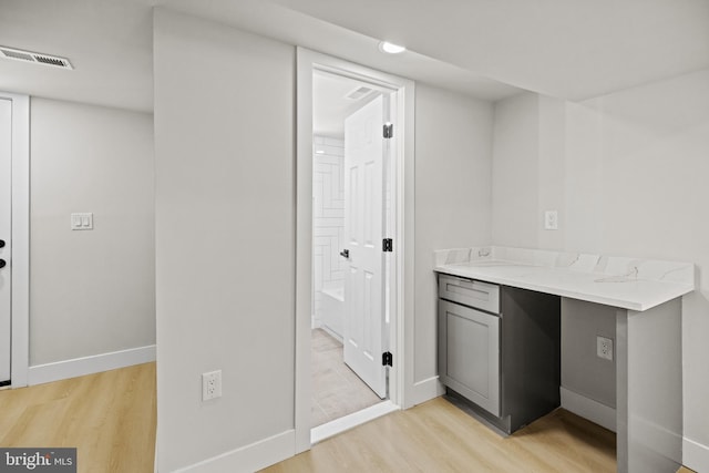 bar with gray cabinets, light wood-type flooring, and light stone countertops