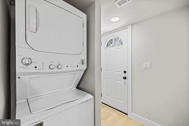 laundry area with light wood-type flooring and stacked washer and dryer