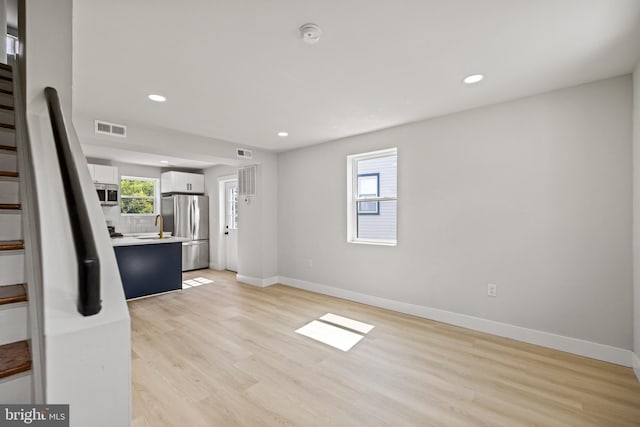 unfurnished living room featuring light wood-type flooring and sink