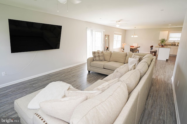 living room with dark wood-type flooring, sink, and ceiling fan