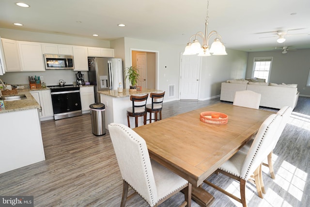 dining area with ceiling fan with notable chandelier, dark hardwood / wood-style flooring, and sink