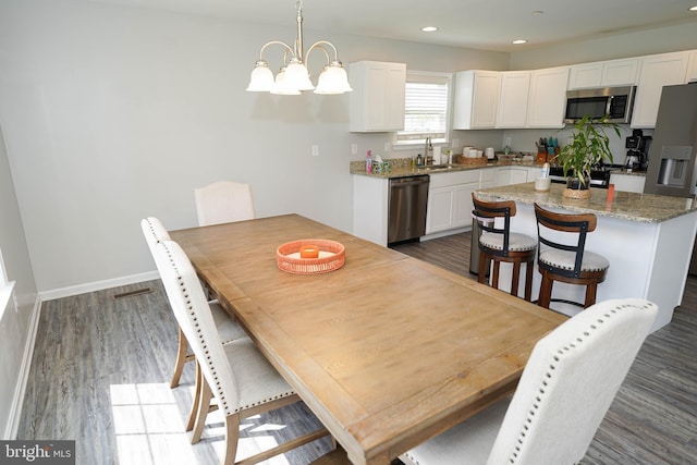 dining space featuring dark hardwood / wood-style flooring, a notable chandelier, and sink