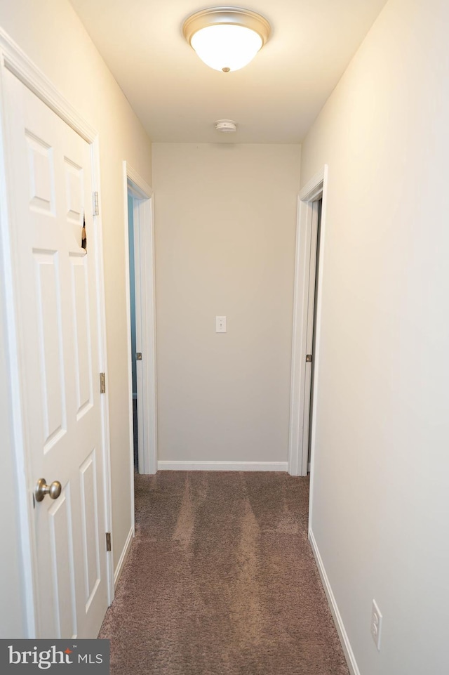 hallway featuring dark colored carpet