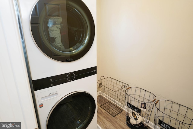 washroom with wood-type flooring and stacked washer and clothes dryer