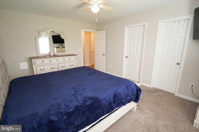 carpeted bedroom featuring ceiling fan and multiple closets