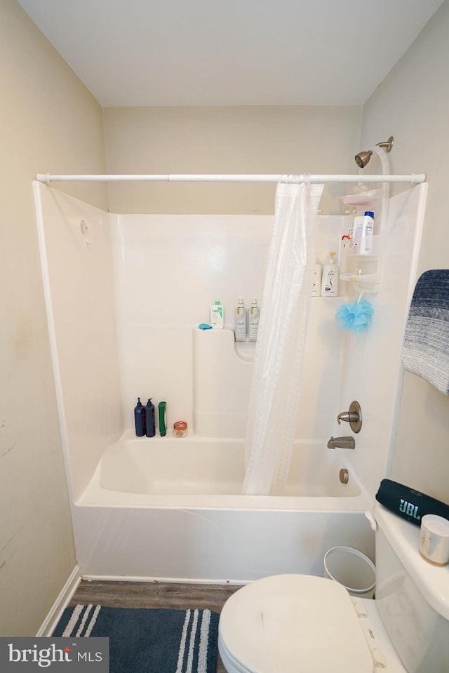 bathroom with toilet, wood-type flooring, and shower / bath combination with curtain