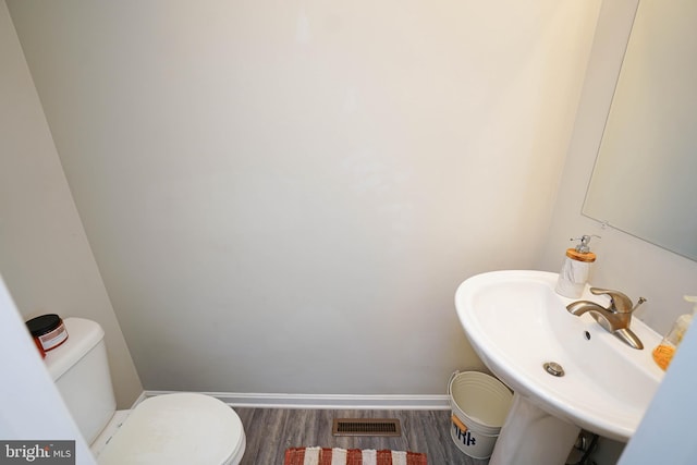 bathroom featuring toilet, sink, and wood-type flooring