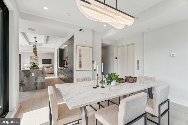 dining space with elevator and light hardwood / wood-style flooring