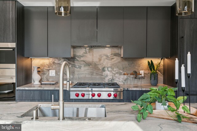 kitchen featuring stainless steel appliances, sink, backsplash, and light stone counters