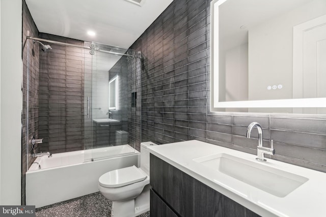 full bathroom with tasteful backsplash, tile walls, vanity, bath / shower combo with glass door, and toilet