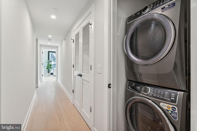 clothes washing area featuring light hardwood / wood-style floors and stacked washer / drying machine