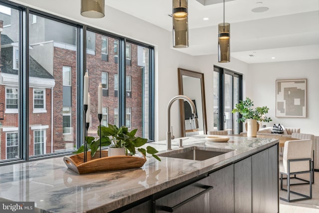 kitchen featuring decorative light fixtures, sink, and light stone counters