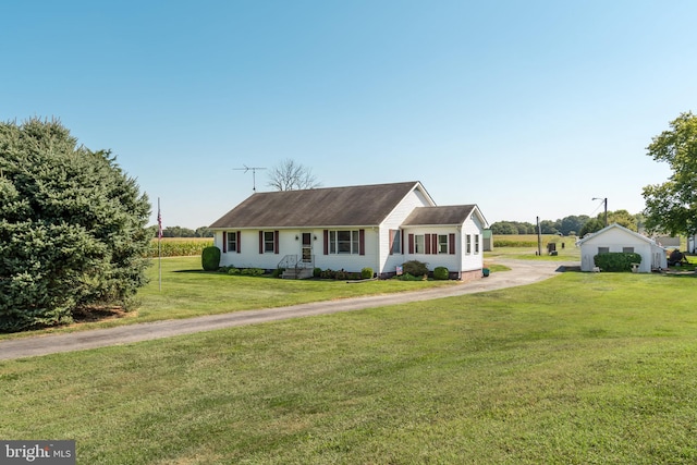 single story home with a front lawn, a porch, an outbuilding, and a garage