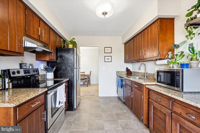 kitchen featuring appliances with stainless steel finishes, light stone counters, and sink