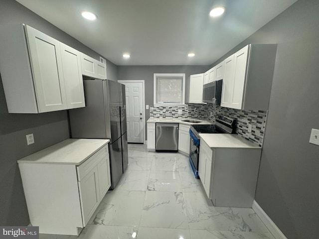 kitchen featuring white cabinets, backsplash, appliances with stainless steel finishes, and sink