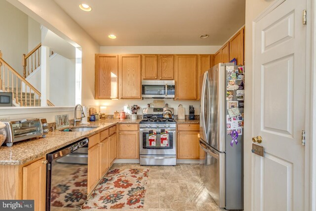 kitchen featuring light brown cabinets, light stone counters, stainless steel appliances, and sink