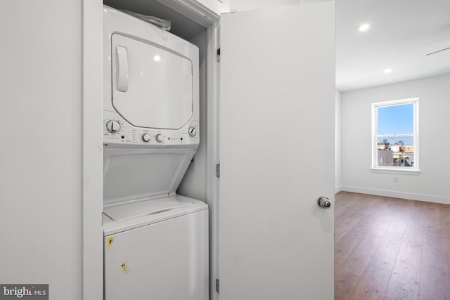 washroom featuring hardwood / wood-style floors and stacked washer and dryer