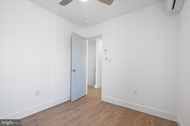 empty room with a wall mounted air conditioner, ceiling fan, and light hardwood / wood-style floors