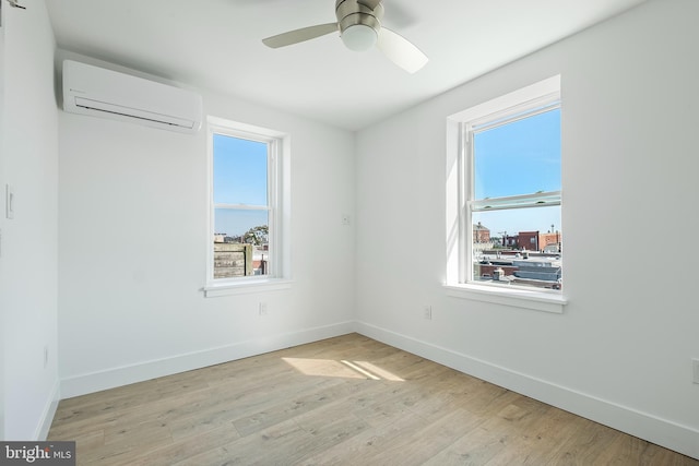 unfurnished room with a wall mounted AC, a wealth of natural light, light hardwood / wood-style flooring, and ceiling fan