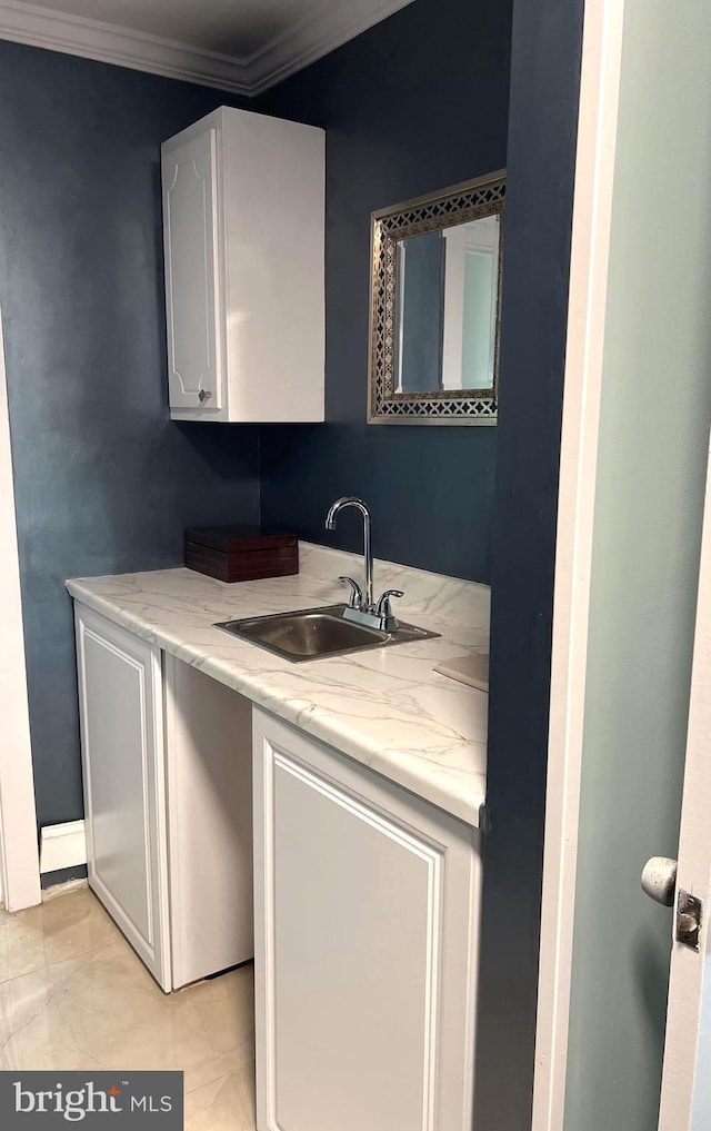 laundry area featuring crown molding, light tile patterned floors, and sink