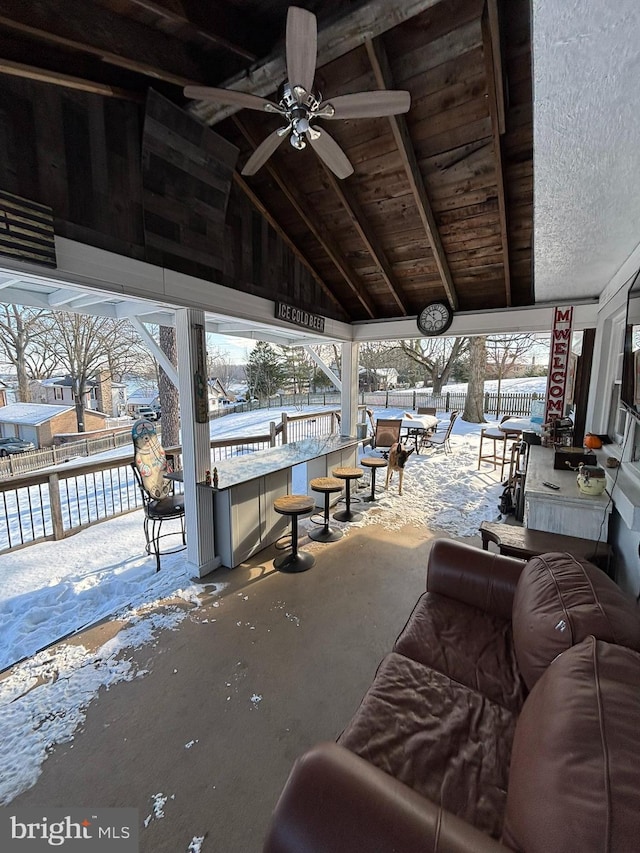 snow covered patio with ceiling fan and a bar