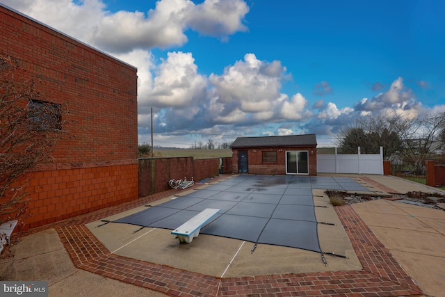 view of pool with a patio area, a diving board, and an outbuilding